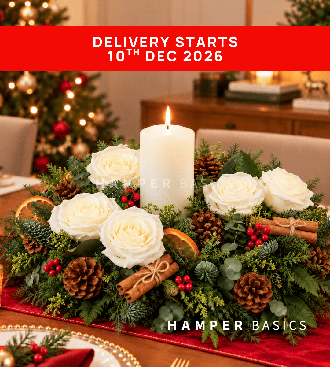 Christmas table centrepiece with white roses, dried orange slices, pine cones, cinnamon sticks, fillers, foliages and candle